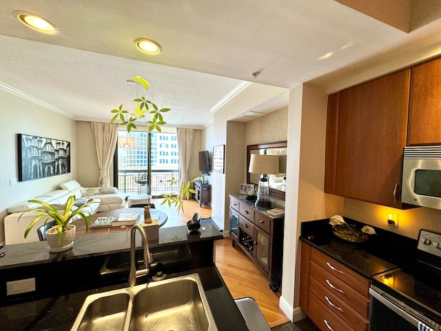 kitchen with light hardwood / wood-style flooring, crown molding, appliances with stainless steel finishes, sink, and a textured ceiling