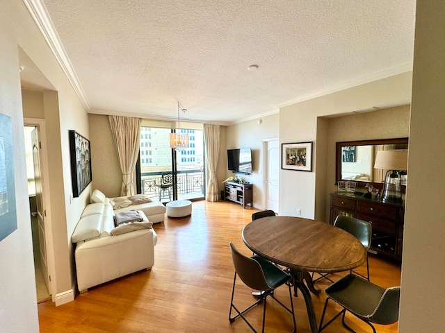 dining room featuring light hardwood / wood-style floors, a textured ceiling, crown molding, and an inviting chandelier