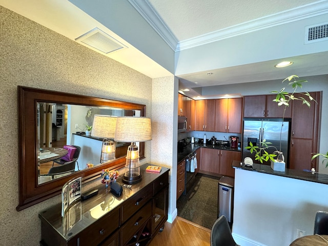 kitchen with ornamental molding, hardwood / wood-style floors, and appliances with stainless steel finishes