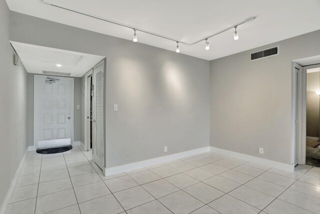 basement featuring rail lighting and light tile patterned floors