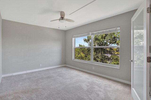 carpeted empty room featuring ceiling fan, french doors, and a water view