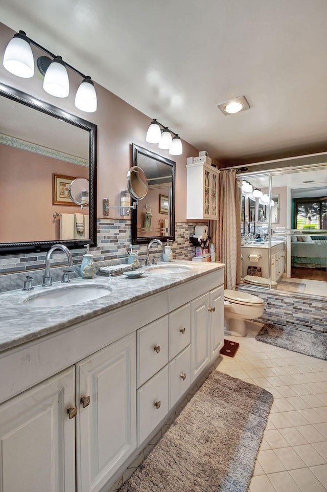 bathroom featuring tile flooring, oversized vanity, toilet, and tasteful backsplash