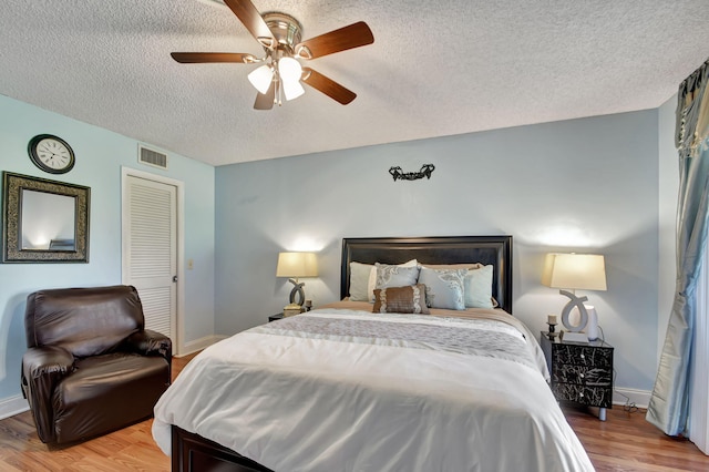 bedroom featuring a textured ceiling, ceiling fan, and light wood-type flooring