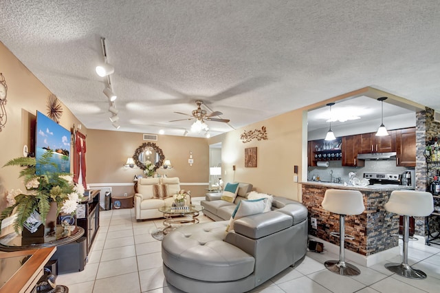 living room featuring ceiling fan, a textured ceiling, light tile floors, and rail lighting