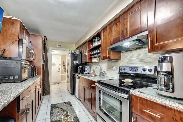 kitchen featuring light stone countertops, stainless steel appliances, backsplash, sink, and light tile floors