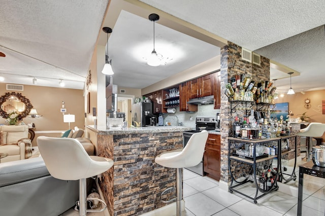 kitchen featuring rail lighting, a textured ceiling, pendant lighting, and light tile floors