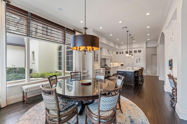 dining room with dark wood-type flooring, sink, and crown molding