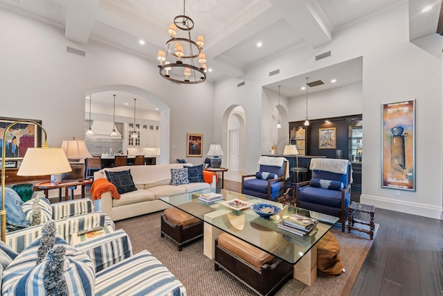 living room featuring beam ceiling, wood-type flooring, an inviting chandelier, a high ceiling, and coffered ceiling