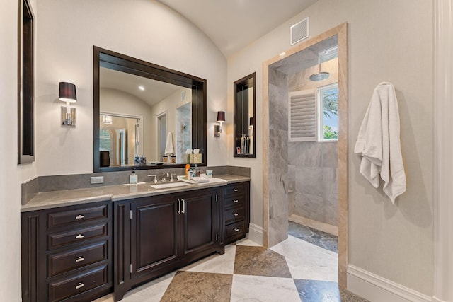 bathroom with tile flooring, lofted ceiling, and vanity