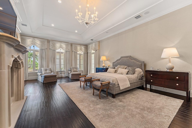 bedroom featuring a chandelier, a fireplace, dark hardwood / wood-style floors, and a raised ceiling