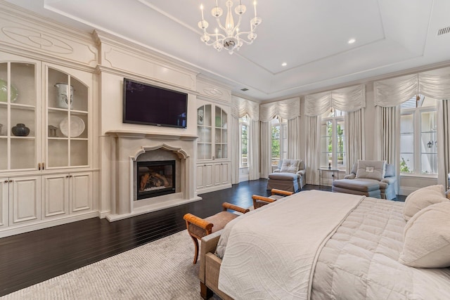 bedroom featuring a tray ceiling, an inviting chandelier, and dark hardwood / wood-style flooring