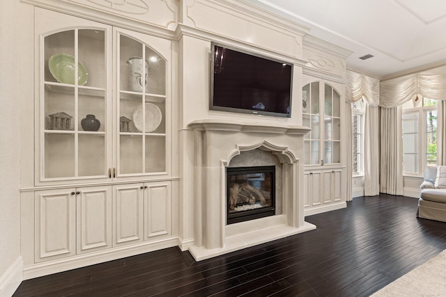 living room featuring dark wood-type flooring, a fireplace, and crown molding