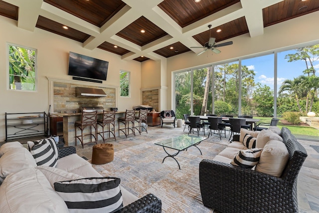 tiled living room with a towering ceiling, a wealth of natural light, coffered ceiling, and ceiling fan