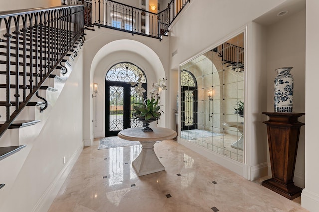 tiled entrance foyer with a towering ceiling and french doors