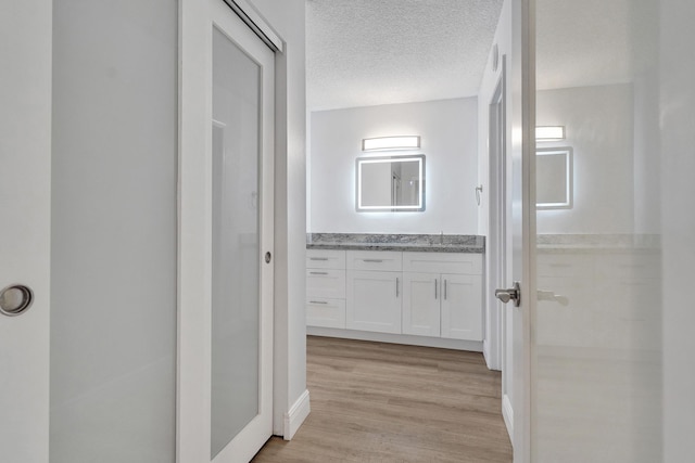 hallway featuring a textured ceiling and light hardwood / wood-style flooring