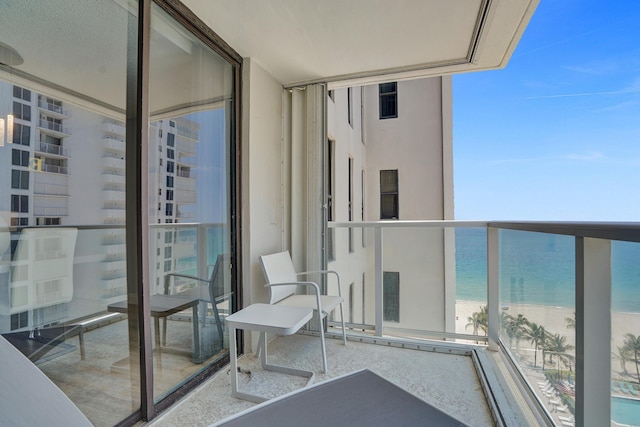 balcony featuring a water view and a beach view