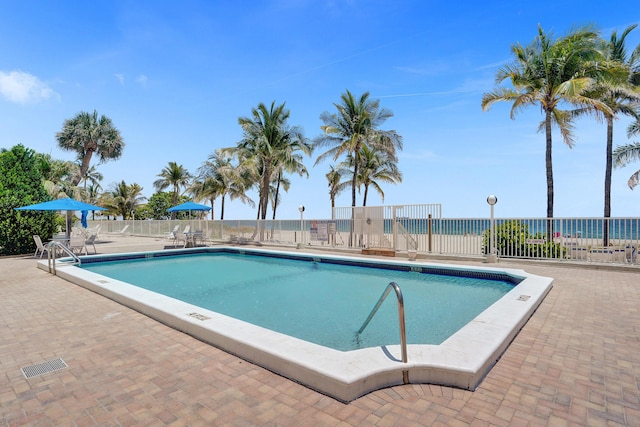 view of pool with a water view and a patio