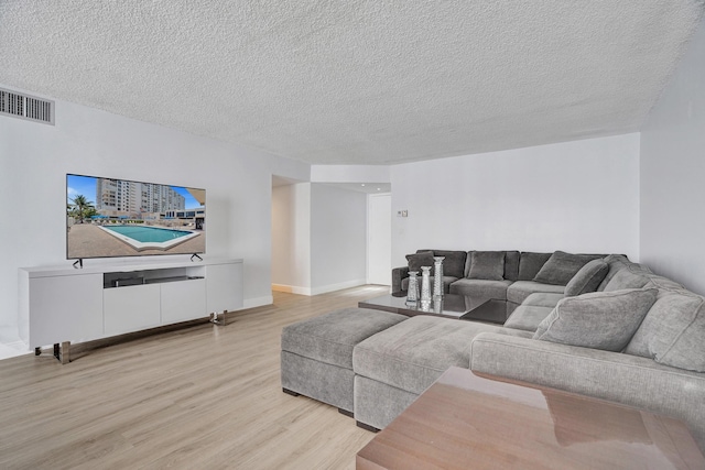 living room featuring light wood-type flooring and a textured ceiling