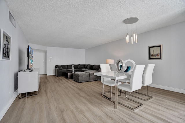 dining room with a textured ceiling and light hardwood / wood-style floors