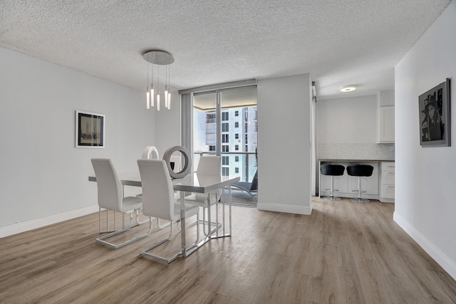 dining space featuring a textured ceiling, light wood-type flooring, and expansive windows