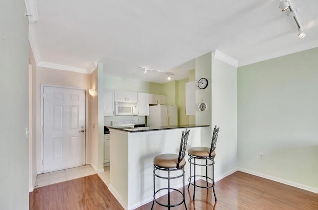 kitchen with white cabinets, white appliances, kitchen peninsula, and light hardwood / wood-style flooring