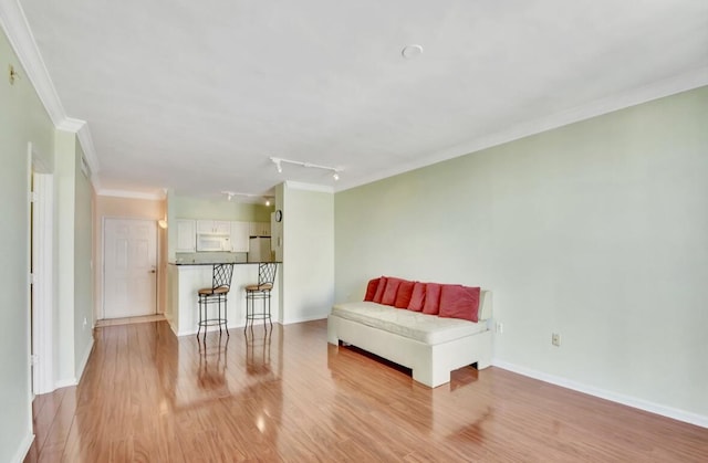 living area featuring light wood-type flooring, track lighting, and crown molding