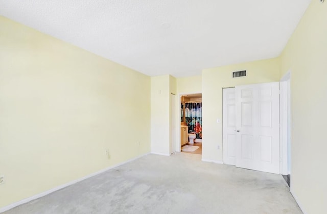 unfurnished bedroom featuring a closet, light colored carpet, and a textured ceiling