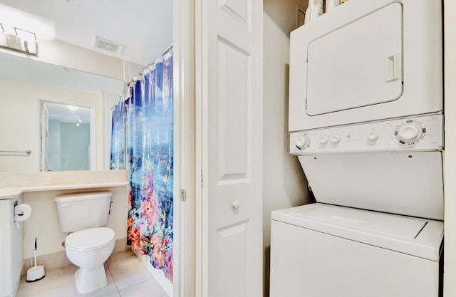 bathroom featuring tile patterned floors, toilet, and stacked washing maching and dryer