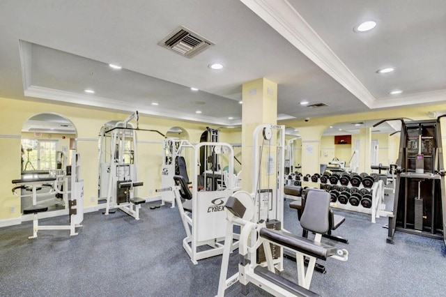 gym featuring a raised ceiling and crown molding