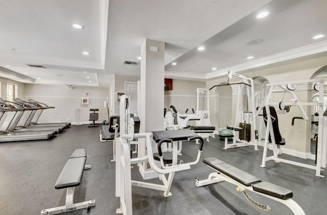 gym with a tray ceiling and ornamental molding