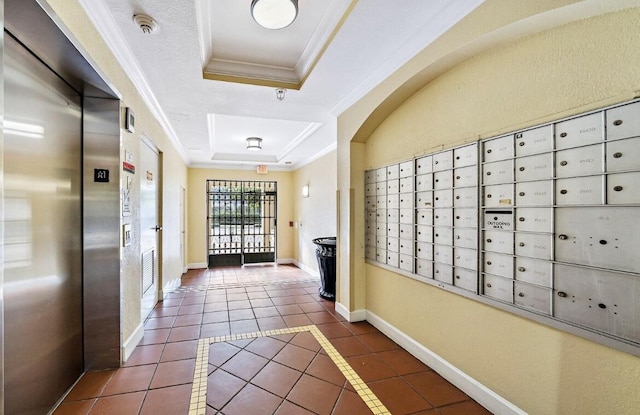 corridor featuring elevator, dark tile patterned floors, mail boxes, crown molding, and a tray ceiling