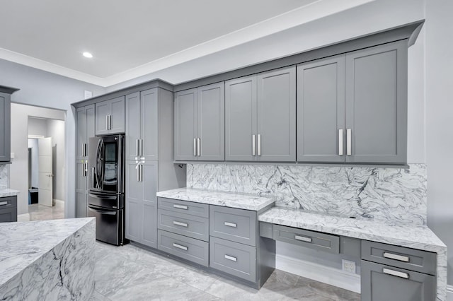 kitchen with gray cabinets, light stone counters, and fridge with ice dispenser