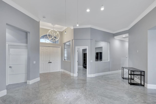 foyer with ornamental molding, a high ceiling, and an inviting chandelier