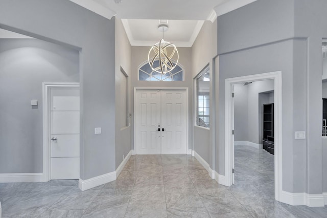 entryway with a high ceiling, an inviting chandelier, and ornamental molding