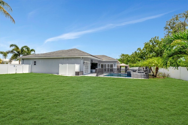 back of property with a fenced in pool, a yard, and a patio