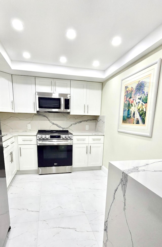 kitchen featuring tasteful backsplash, light stone counters, white cabinets, and stainless steel appliances