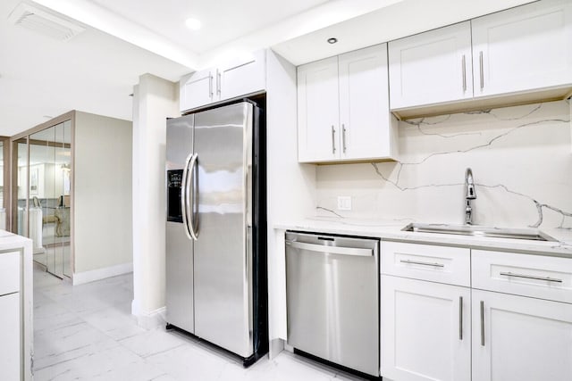 kitchen with backsplash, sink, white cabinetry, light stone countertops, and appliances with stainless steel finishes