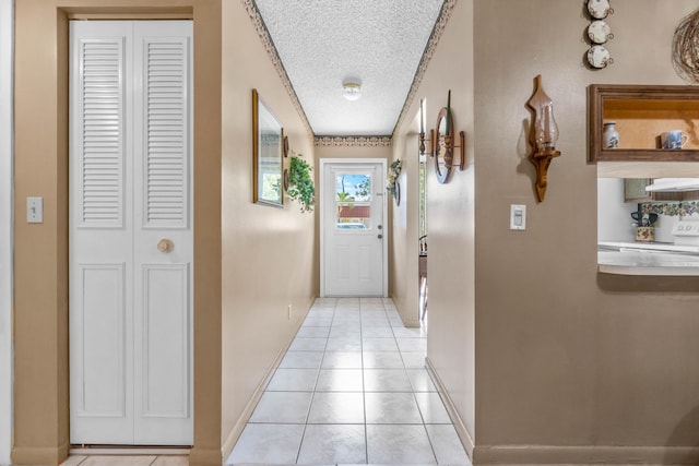 hall with a textured ceiling and light tile patterned floors