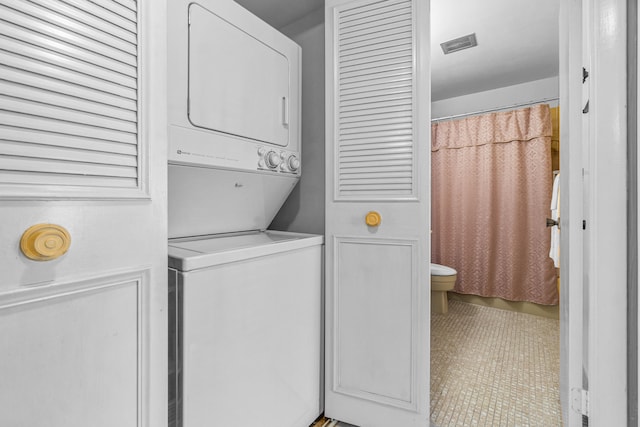 laundry area featuring stacked washer and dryer and light tile patterned flooring