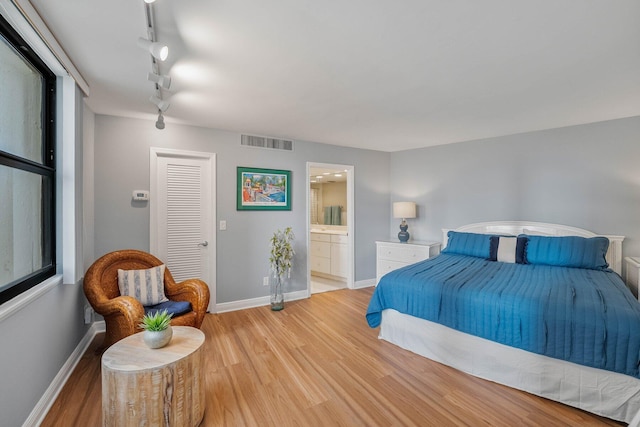 bedroom with track lighting, hardwood / wood-style floors, and ensuite bath