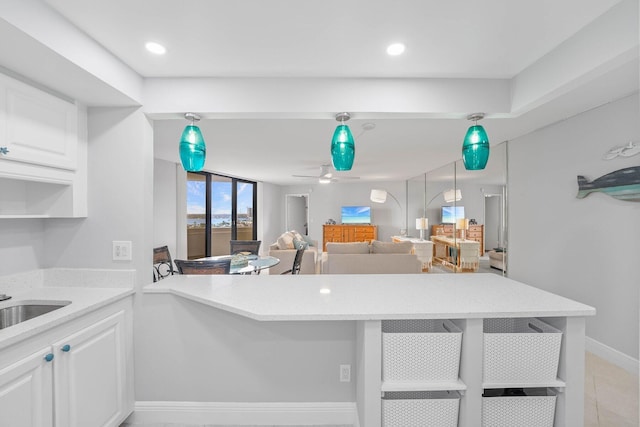 kitchen with pendant lighting, ceiling fan, sink, and white cabinets