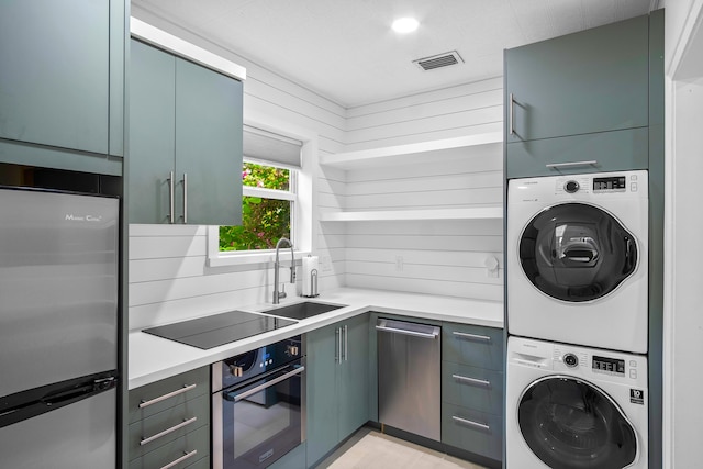 kitchen with sink, stacked washer / dryer, and appliances with stainless steel finishes