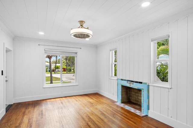 unfurnished living room with hardwood / wood-style flooring, crown molding, and wood walls