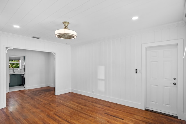 unfurnished room featuring wooden walls, dark hardwood / wood-style floors, and ornamental molding