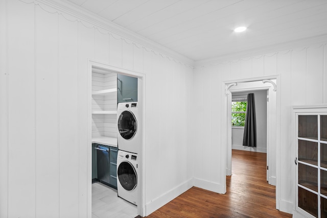 laundry area with wooden walls, ornamental molding, stacked washing maching and dryer, and hardwood / wood-style flooring