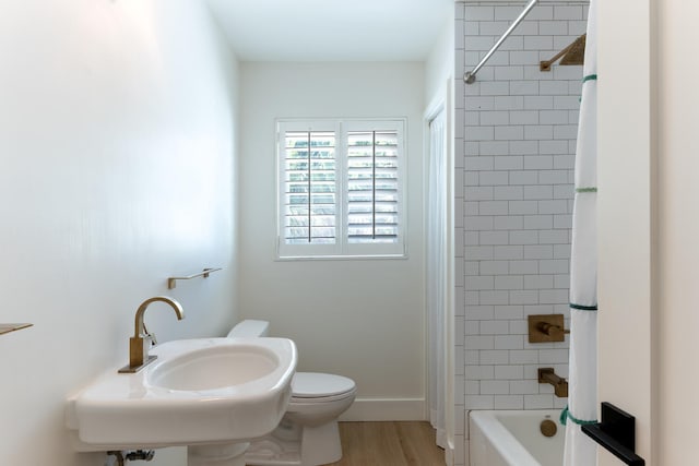 bathroom with wood-type flooring, toilet, and tiled shower / bath combo