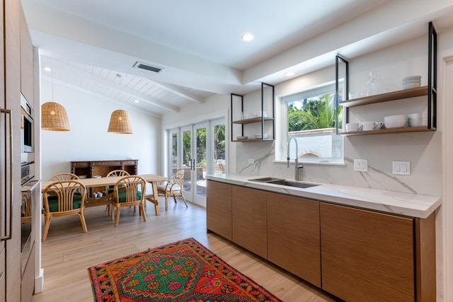 kitchen featuring a healthy amount of sunlight, light hardwood / wood-style floors, tasteful backsplash, and vaulted ceiling with beams