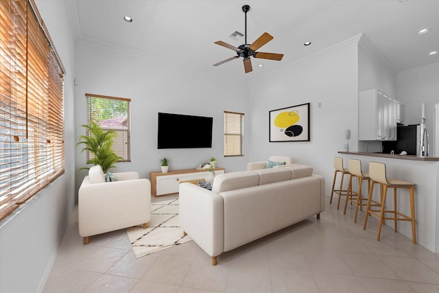 living room with light tile patterned floors, ceiling fan, crown molding, and a high ceiling