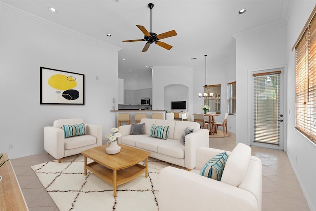 tiled living room with ceiling fan with notable chandelier, ornamental molding, and a towering ceiling