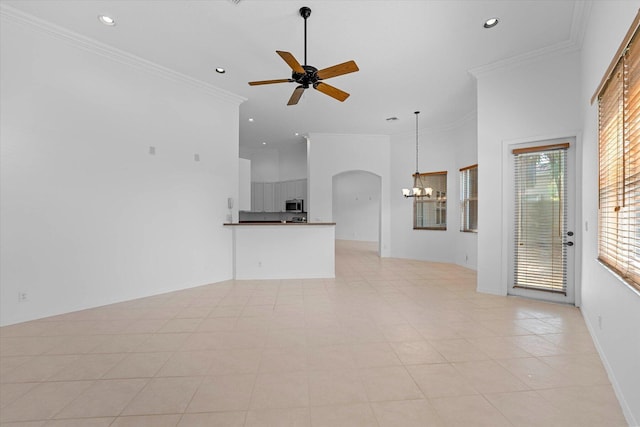 unfurnished living room featuring crown molding, light tile patterned floors, a towering ceiling, and ceiling fan with notable chandelier